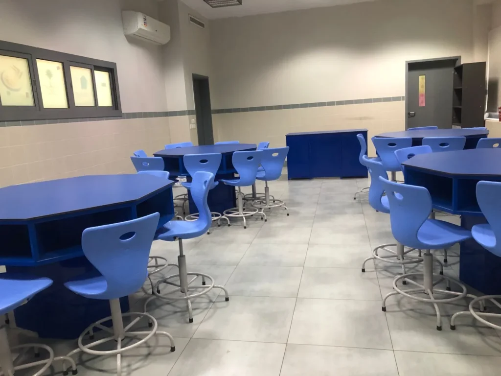 كراسي وطاولات دراسية باللون الأزرق داخل فصل دراسي حديث مصمم لتجهيز الروضات
